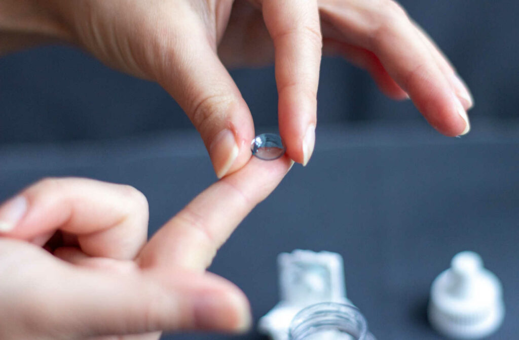 A hand placing a a customized scleral contact lenses on their finger tip to help achieve more comfortable and clear vision