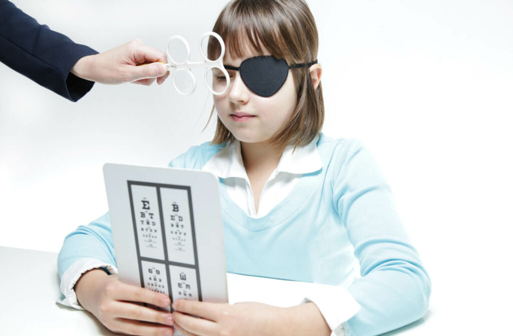 A young girl with an eye patch is undergoing vision therapy with a use of prism flippers to measure the misalignment of the eyes, to induce misalignment to facilitate various tests and to treat misalignment