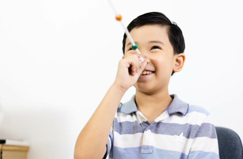 A boy is holding a string with colored beads placed at the tip of his nose. Brock string exercise is commonly used in vision therapy for vergence problems, such as convergence insufficiency, amblyopia (lazy eye), and strabismus (eye turn), to improve double vision, blurred vision, headaches, visual discomfort, dizziness, and imbalance.