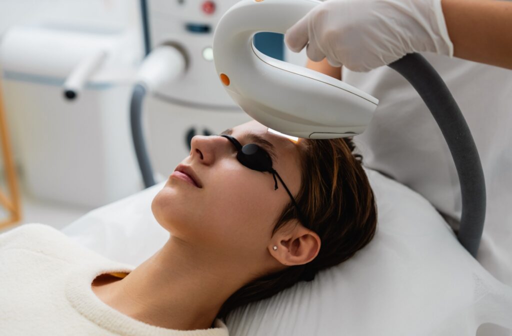 a woman is using an IPL laser to help treat her eye health ailments, such as dry eye disease.