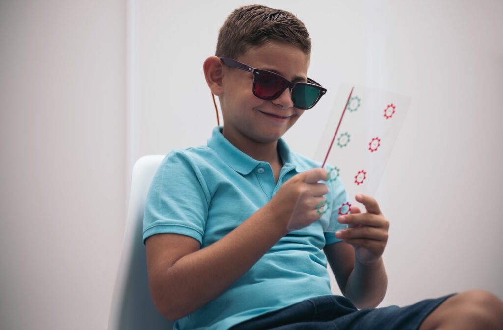 A young boy at the eye doctor wearing colored glasses while doing a vision therapy exercise.