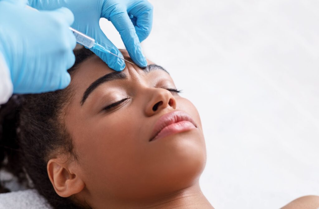 A close-up of a woman receiving a botox injecting on her brows.