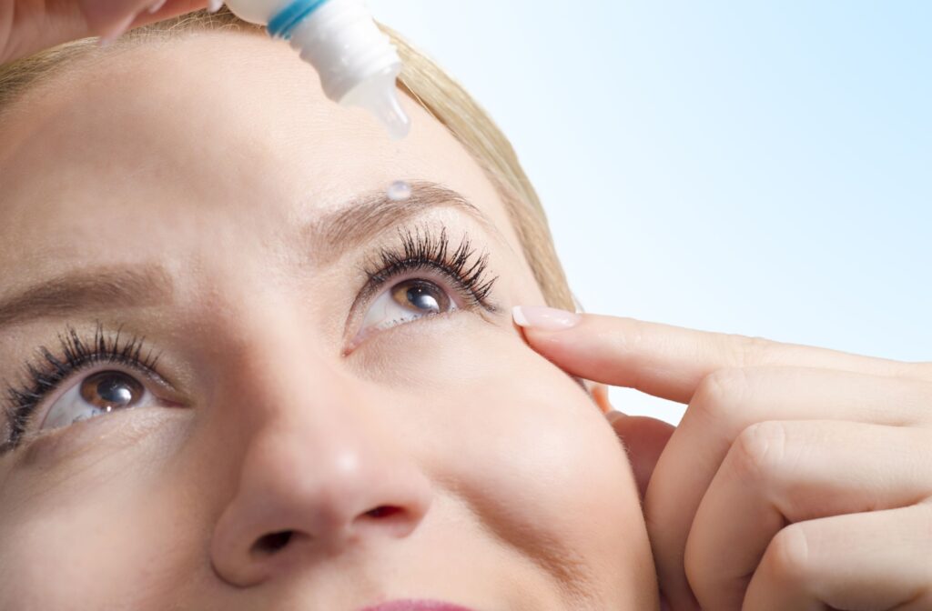 A woman applying eyedrops on her left eye.