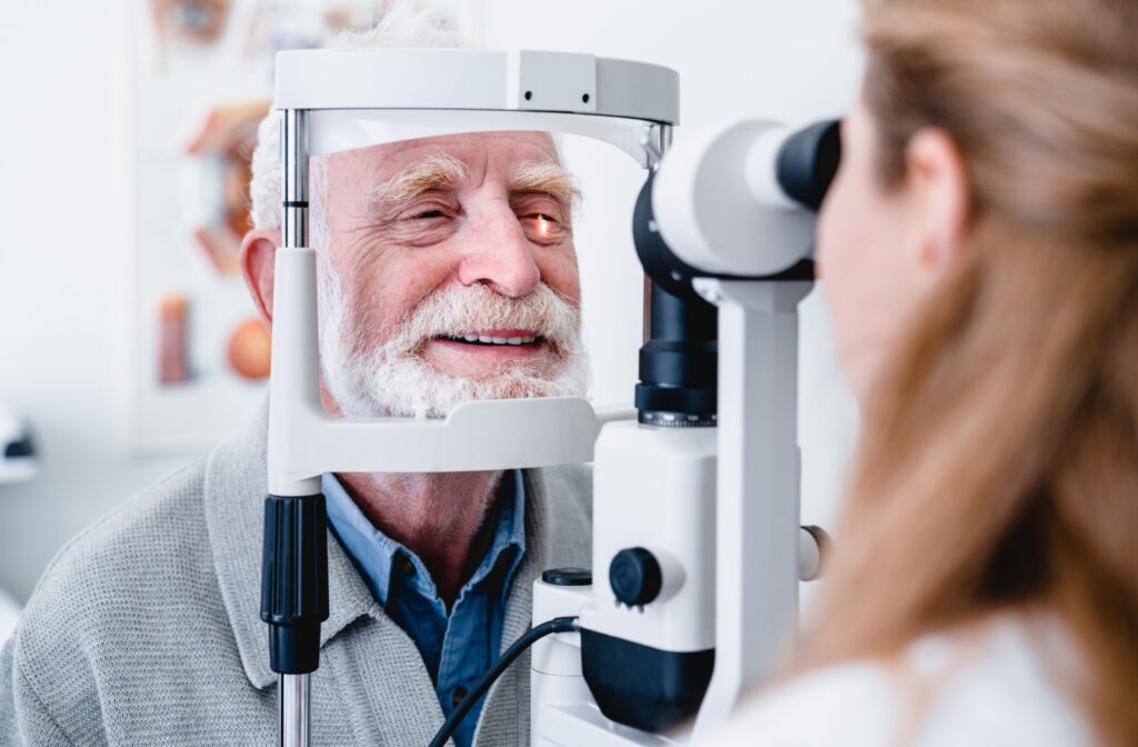 An older adult smiling during a slit-lamp eye exam to learn what's causing a sudden improvement in vision.