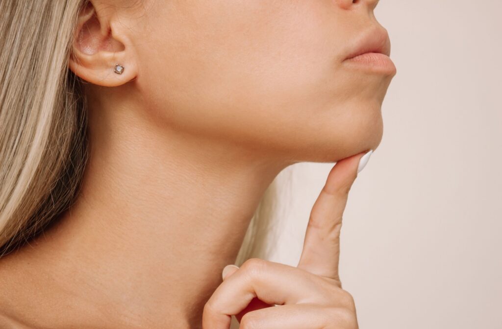 A cropped photo of a woman resting her chin on her pointer finger.