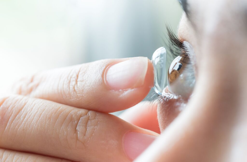 A woman applies a scleral contact lens to her eye.