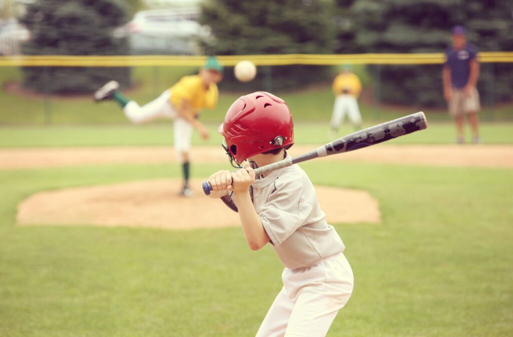 A young person at bat in a youth baseball game preparing to hit a pitch.