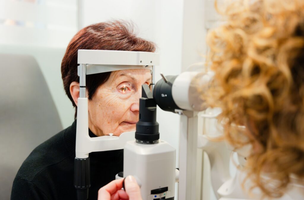 An older adult undergoing an eye exam using a slit lamp microscope.