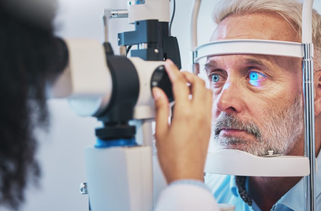 A person undergoes an eye pressure test using a slit lamp as blue light reflects off their eye.