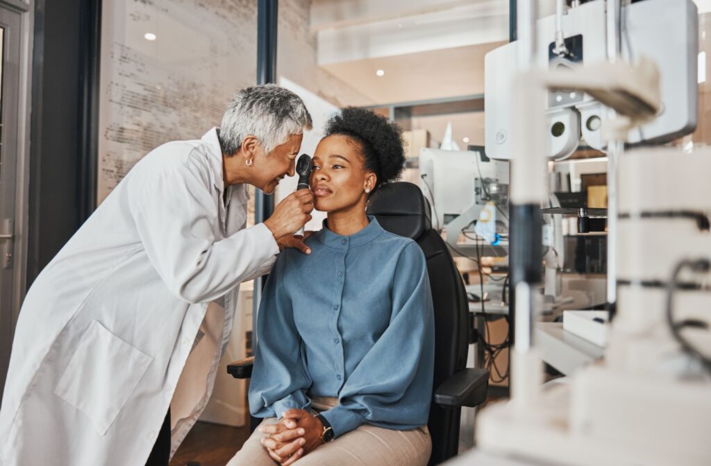 An optometrist examines a seated patient’s eye using a handheld tool during an eye exam.