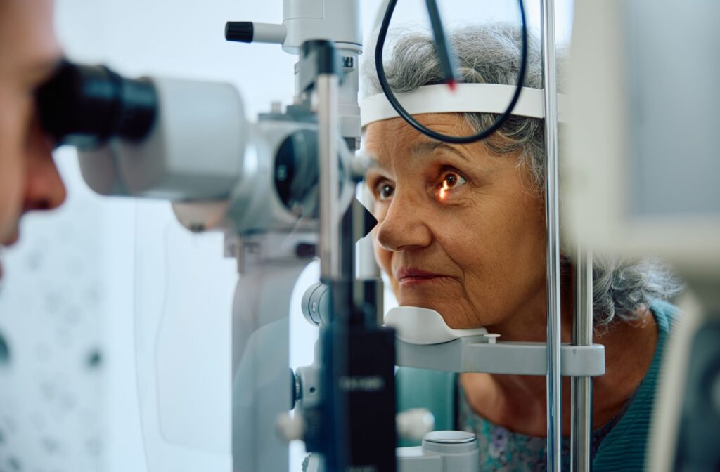 An older person sits at an eye doctor’s office undergoing an eye exam.