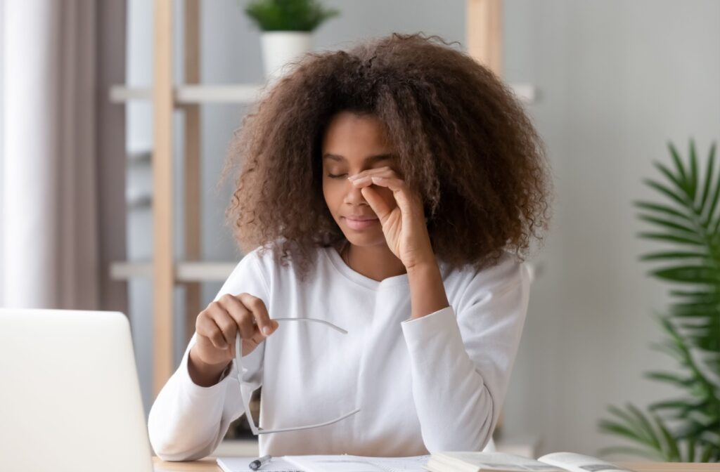 Woman holding her glasses in her hand as she uses her other hand to rub her eyes