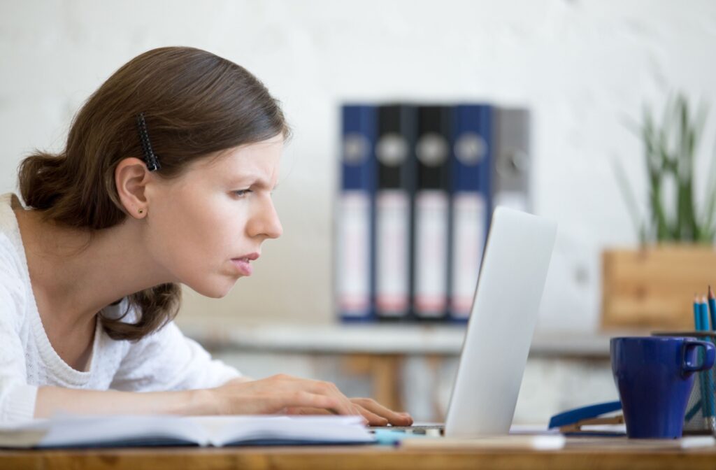 Woman leaning close to a computer screen and squinting to try to see better