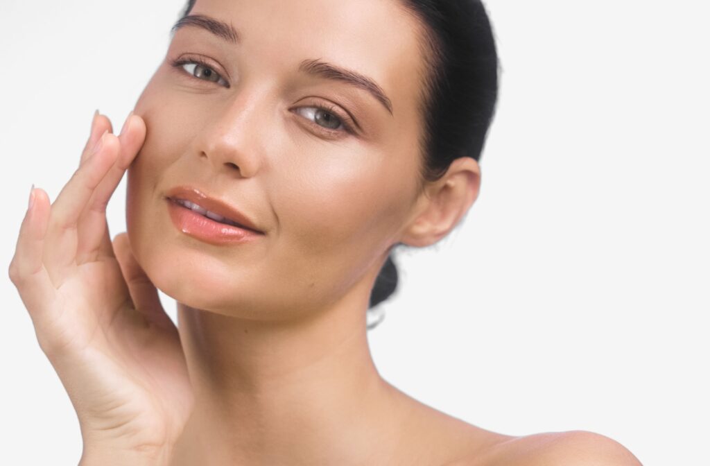 A model with flawless skin touches their skin in admiration