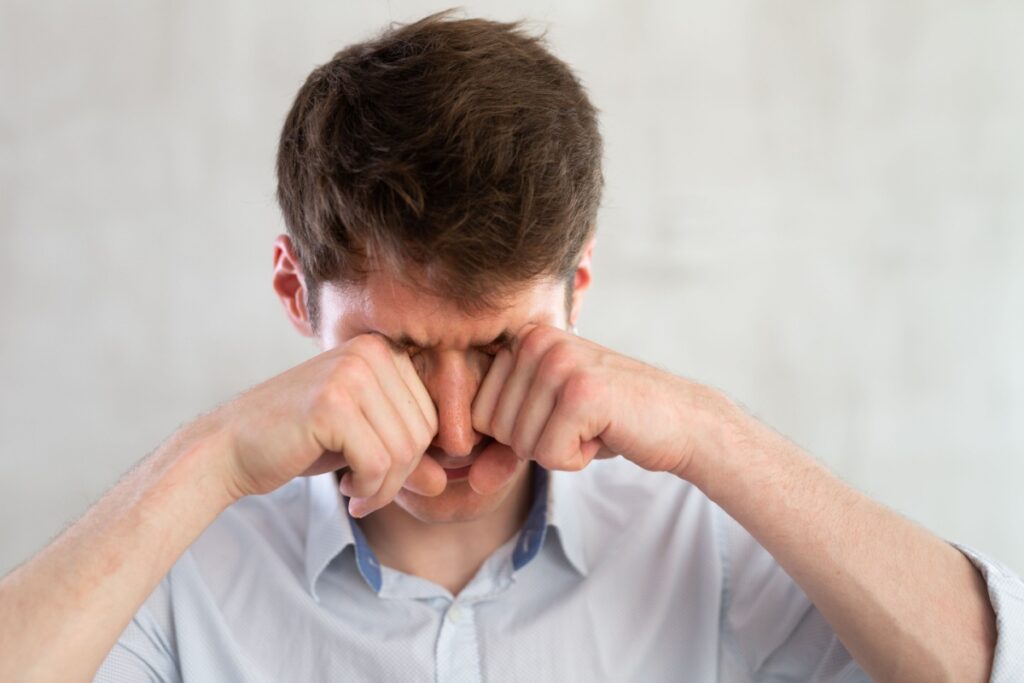 A person rubbing their irritated eyes