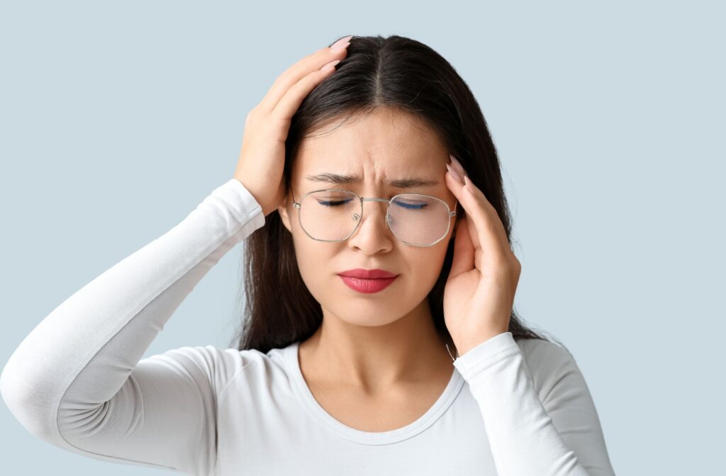 A person holding their hands up to their in discomfort from a headache caused by sensitivity to a light source