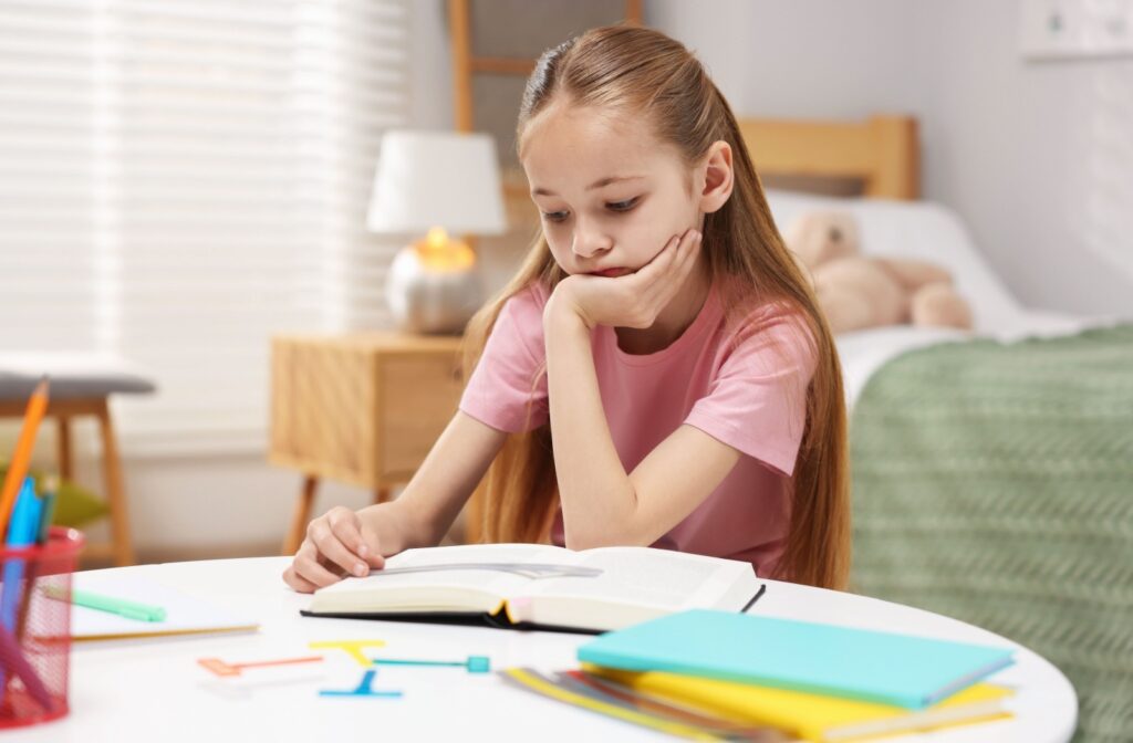 A young child sitting at a table and reading a book